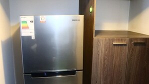 A stainless steel Samsung refrigerator in a kitchen with wooden cabinets and a tiled floor. - Tranquilo Departamento Full Equipado (Santiago)