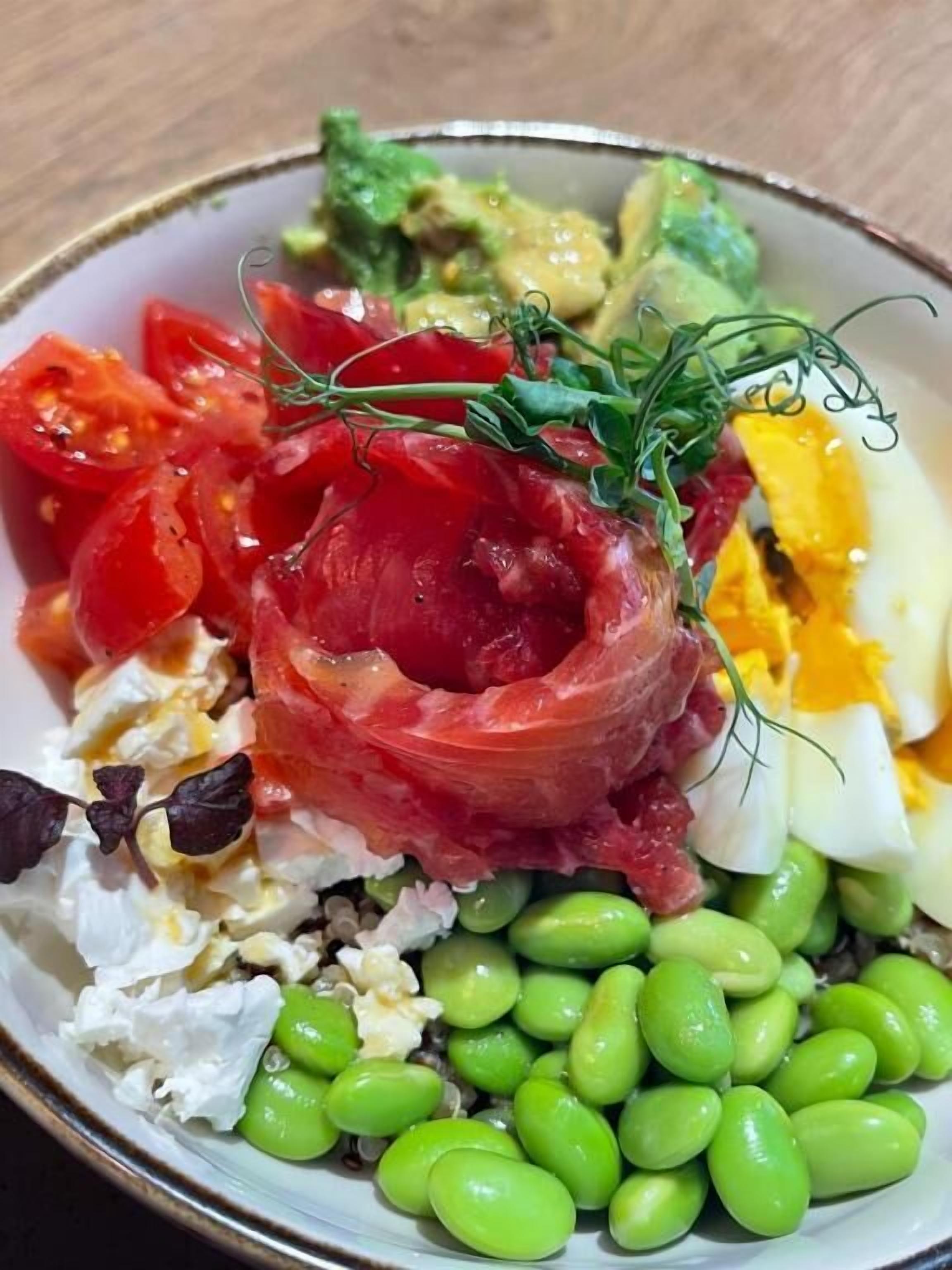 Eine Salatschüssel mit verschiedenen Zutaten, darunter Tomaten, Avocado, Eier und grüne Bohnen.