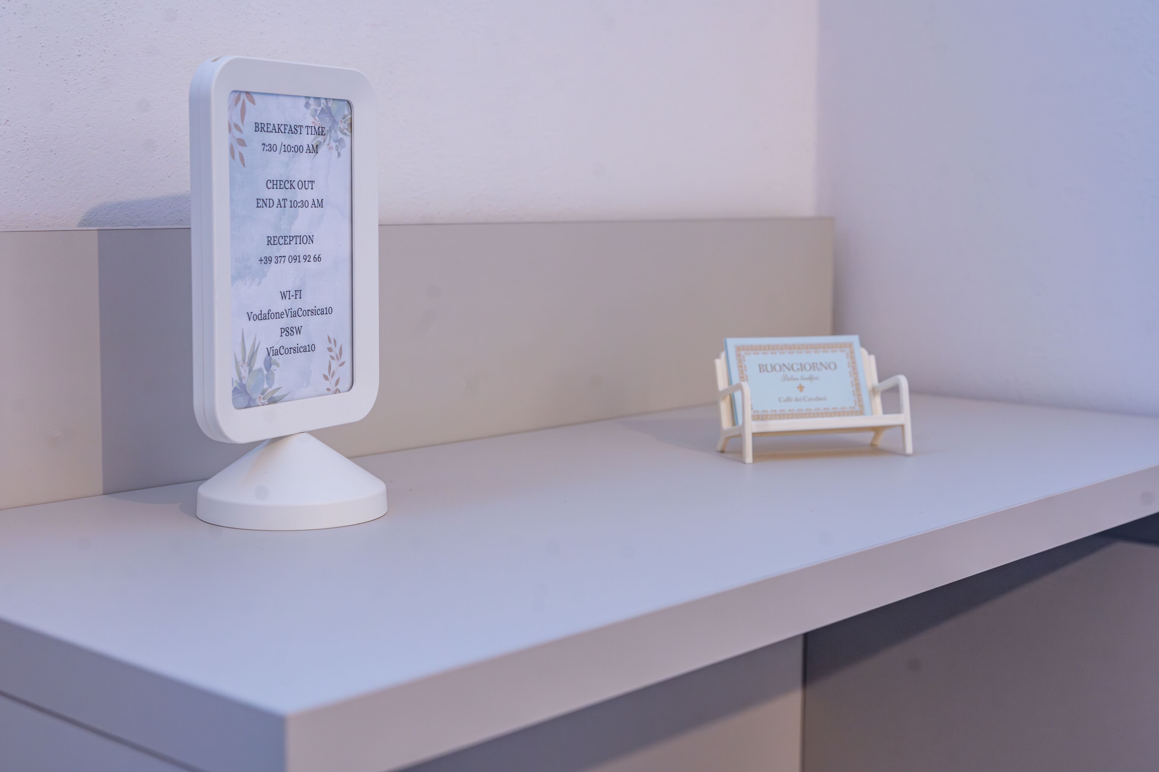 Een receptiebalie met een digitaal display en een klein naambordje.