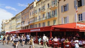 Una calle con cafés y gente caminando.