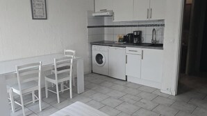 Una cocina compacta con lavadora, cafetera y lavamanos.