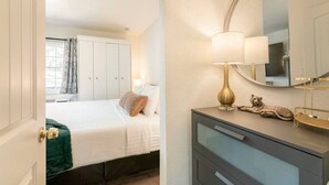 Une chambre d’hôtel avec un lit, une commode, un miroir et une lampe.