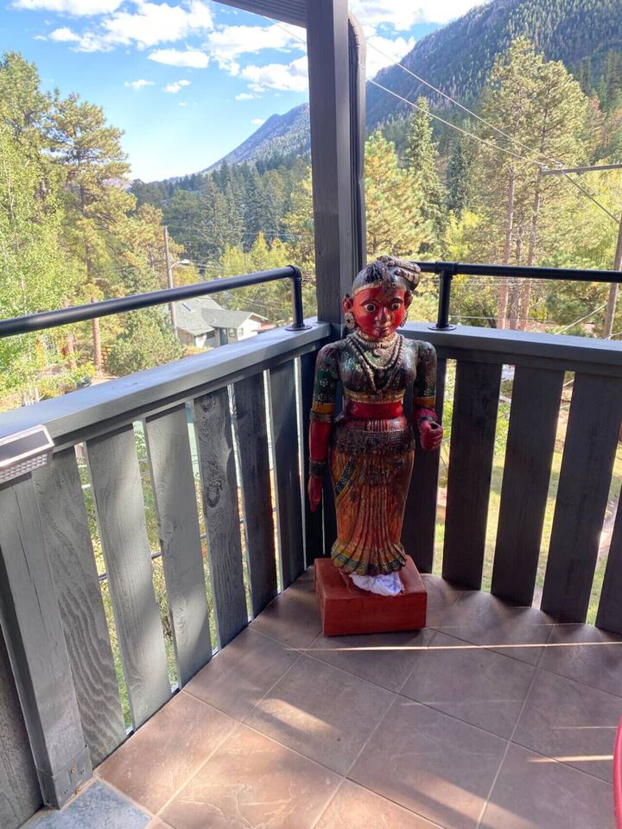 A statue on a balcony with a mountain view.