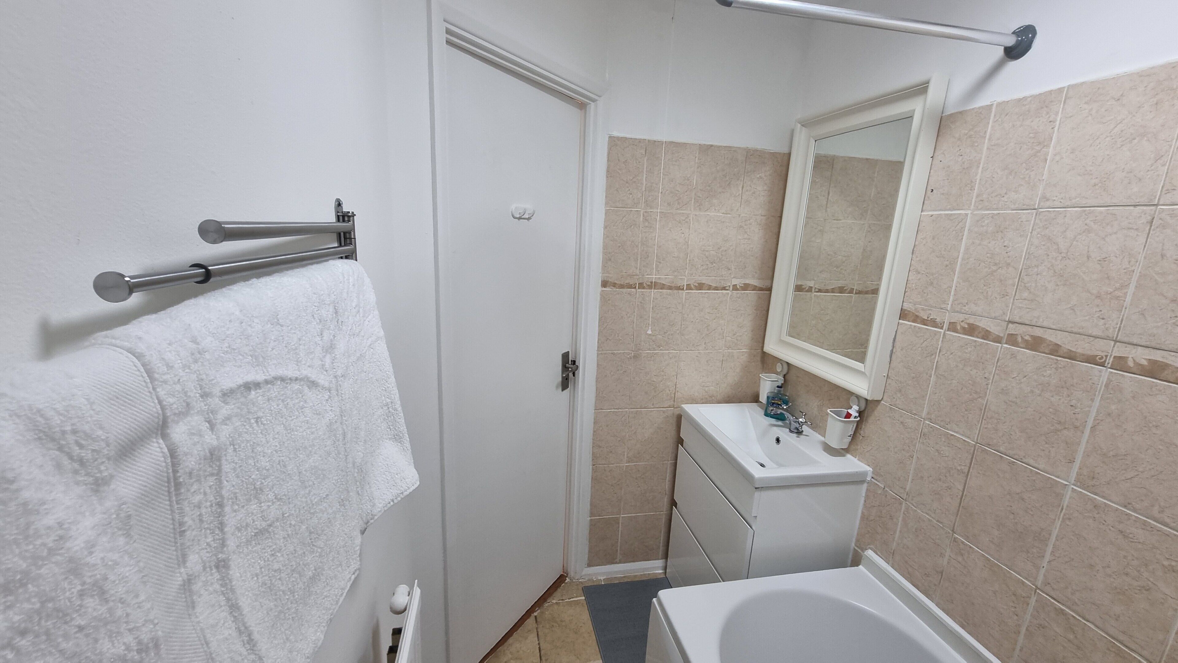 A small bathroom with a white sink, a mirror, and a towel rack.