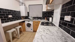 Une cuisine de taille réduite équipée d’un lave-linge, d’une cuisinière à gaz et d’un évier.