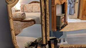 Ein Zimmer mit einem großen, verzierten Spiegel, einem Kamin und einem Bett mit floralem Bettzeug.