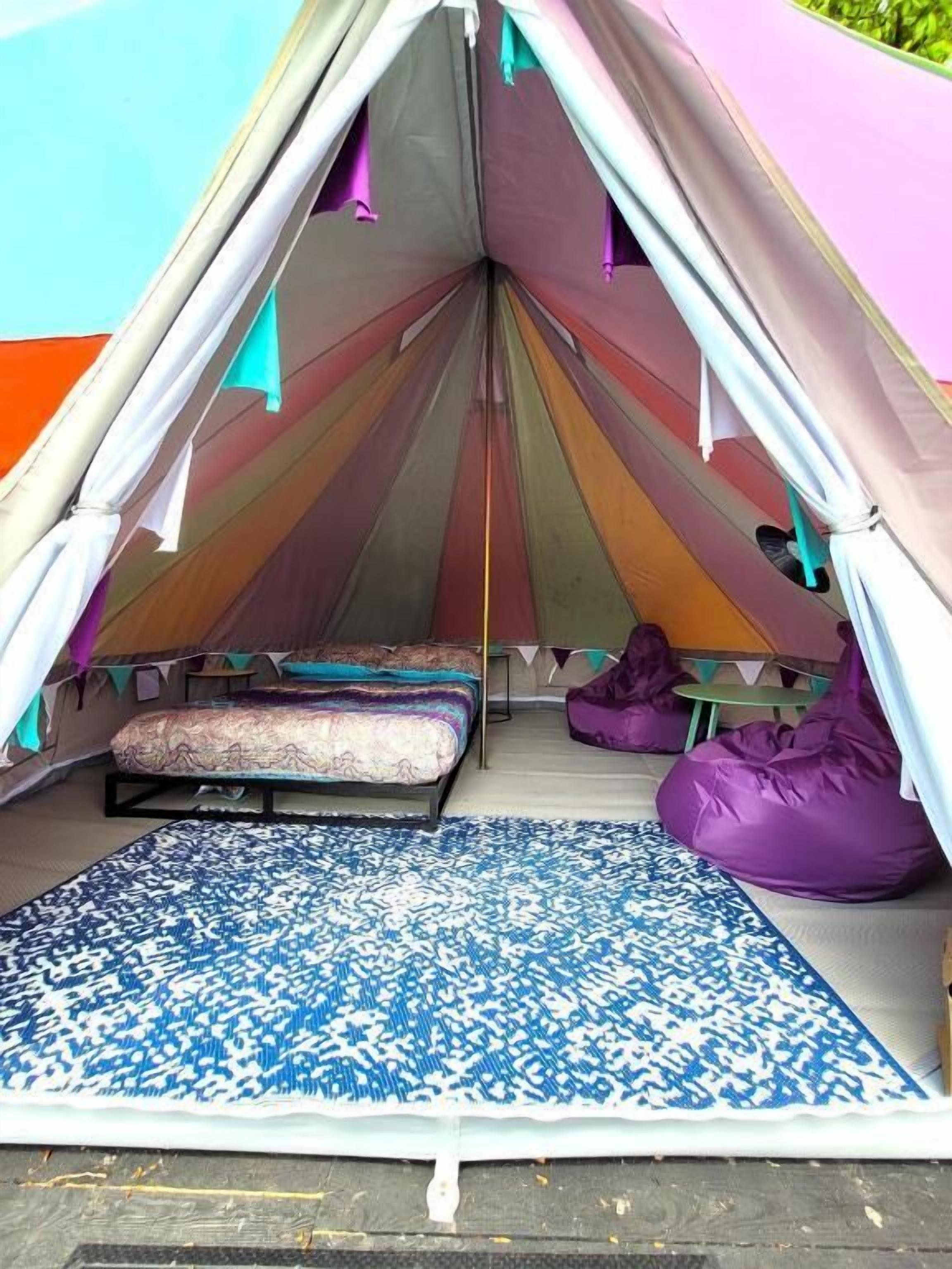 Una tienda de campaña con una cama y pufs en su interior.