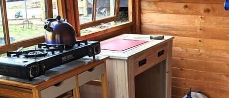 A kitchen with a gas stove, wooden shelves, and a checkered floor.