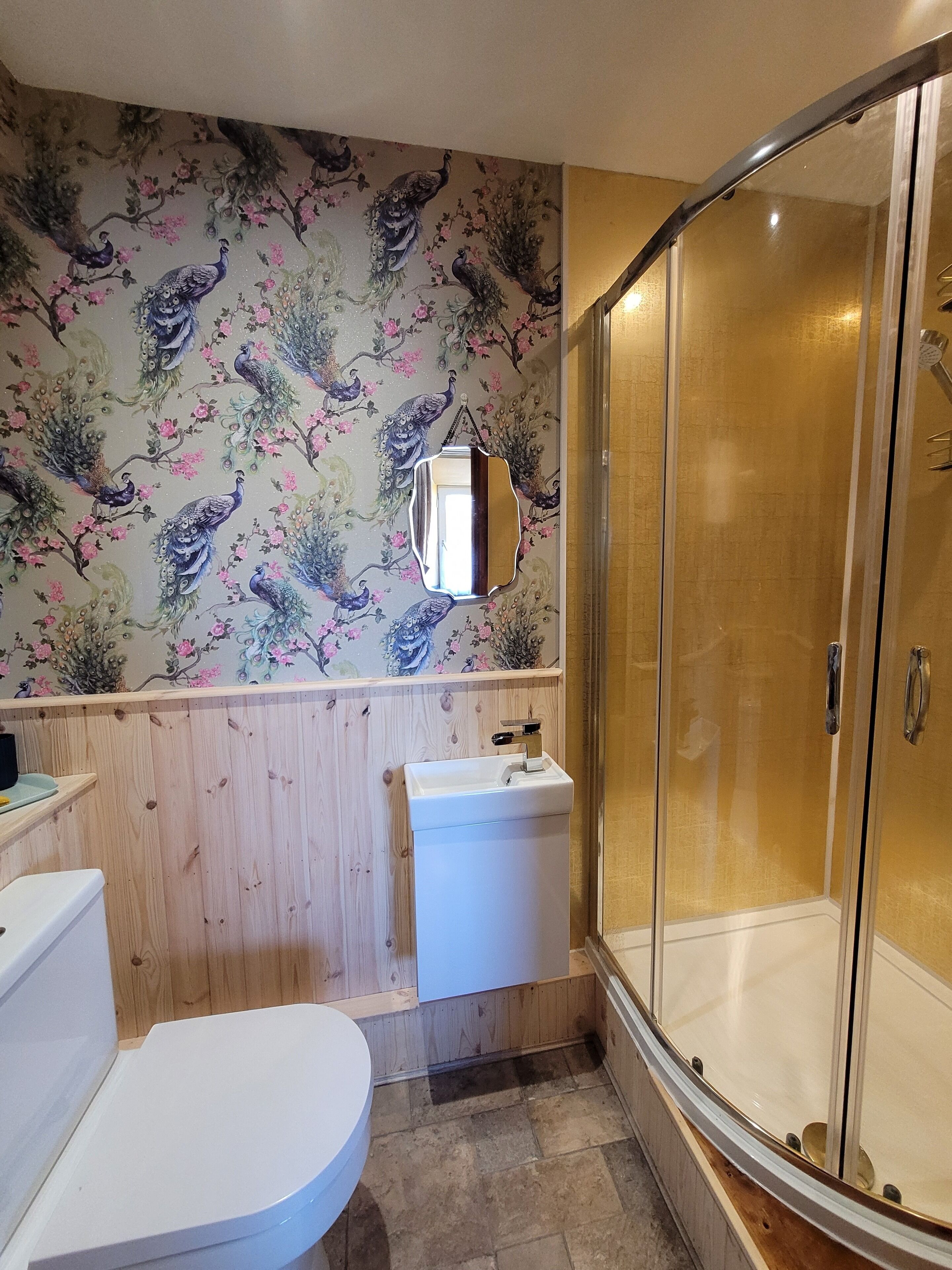 A bathroom with a wooden vanity, a white sink, a toilet, and a glass-enclosed shower.