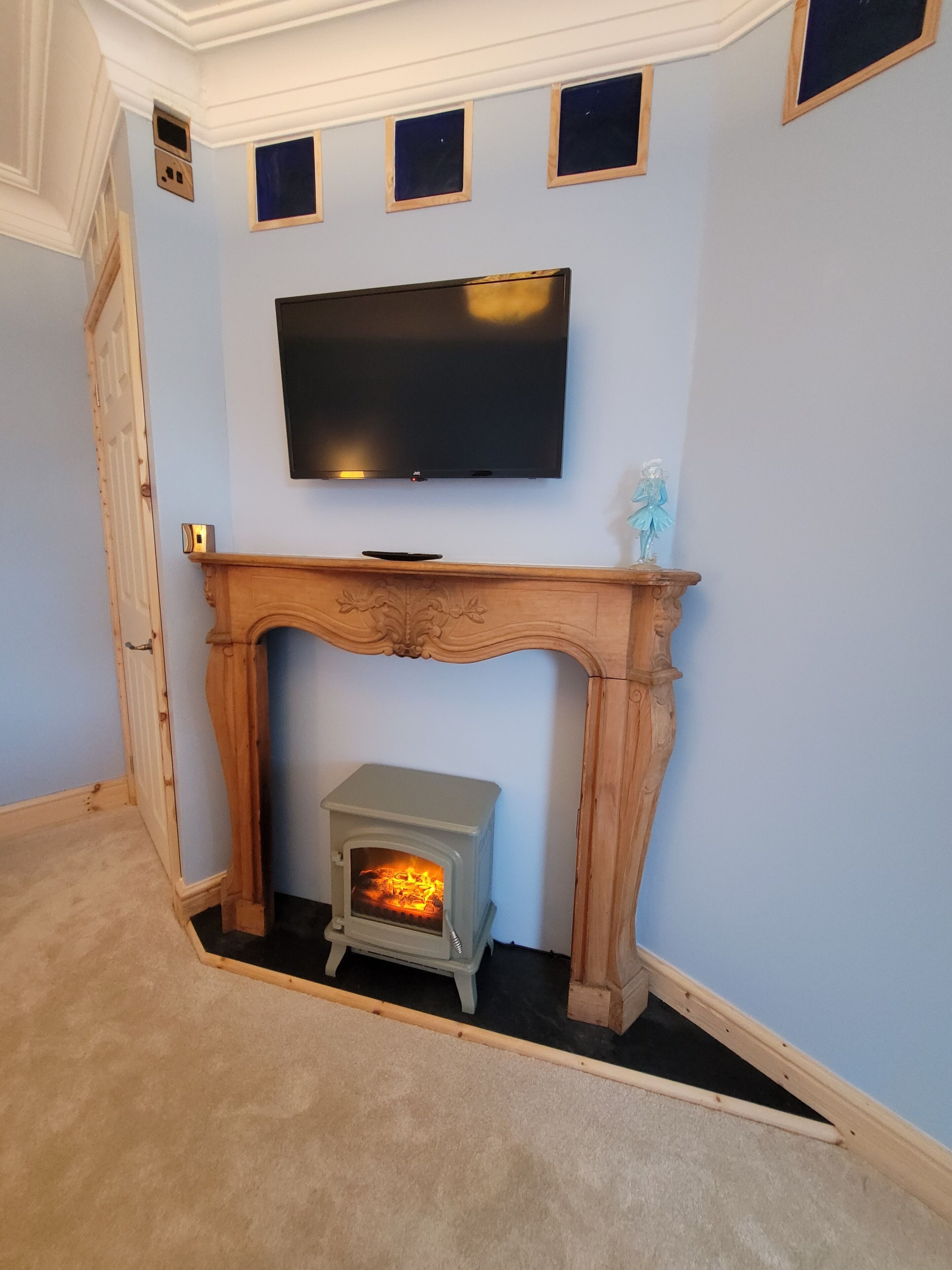 Una habitación con chimenea, un televisor sobre ella y una pequeña figura decorativa en la repisa.