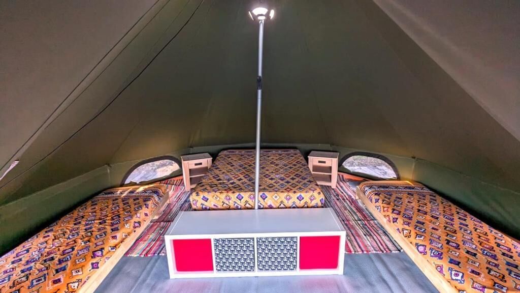 A tent with a central sleeping area and two smaller beds on either side.