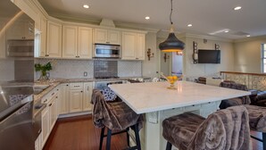 A modern kitchen with white cabinetry, a large island, bar stools, and a pendant light. - Luxury 2 bed 1 bath in nice neighborhood. (Torrance)