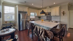 A modern kitchen with white cabinets, stainless steel appliances, and a large island with bar stools. - Luxury 2 bed 1 bath in nice neighborhood. (Torrance)