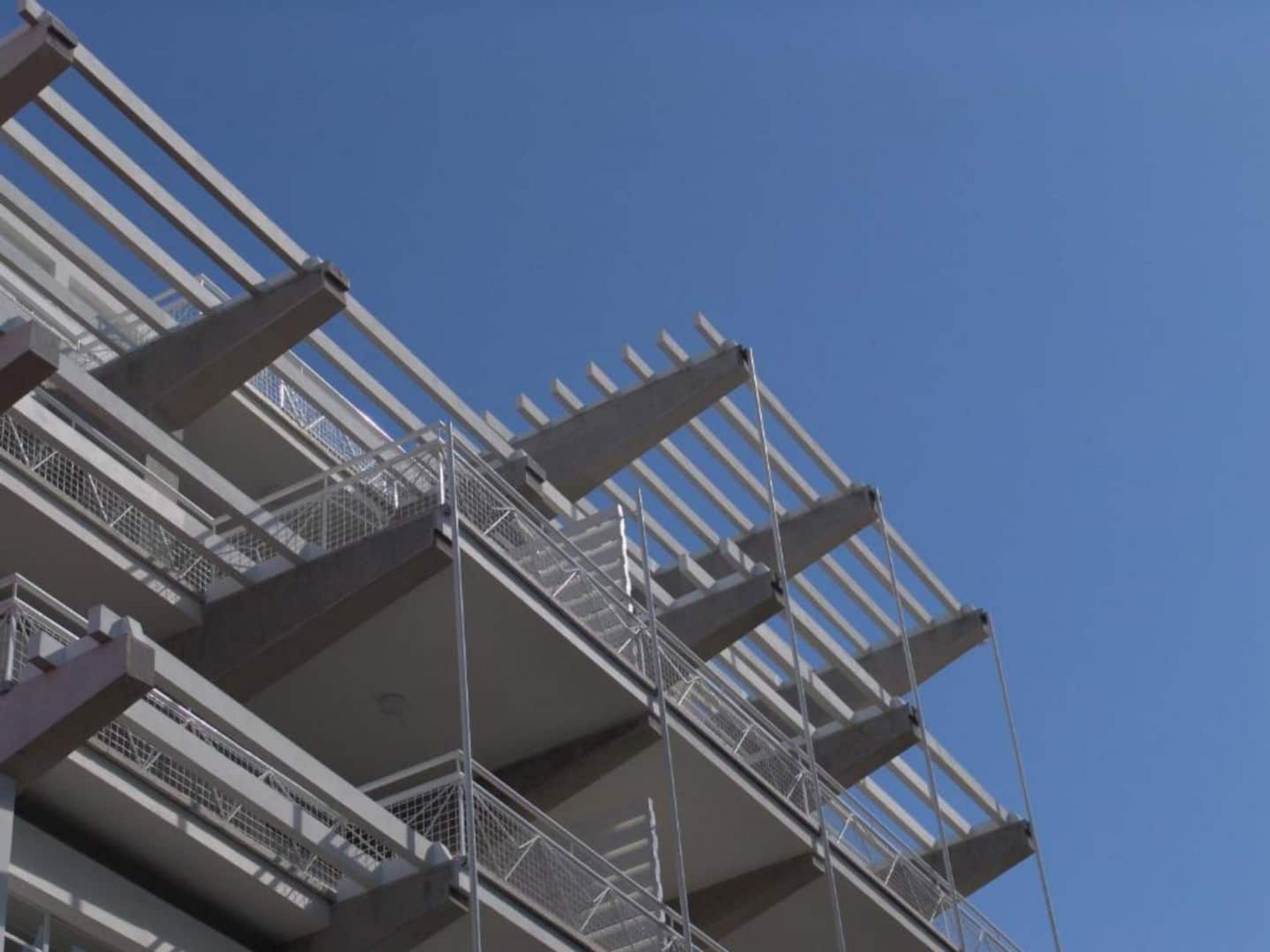 Een meerlaags gebouw met een modern architectonisch ontwerp, voorzien van een reeks balkons en wenteltrappen.