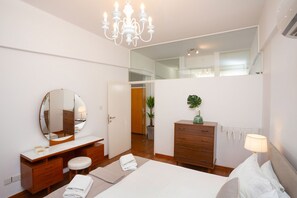 Un dormitorio moderno con una cama grande, un aparador de madera, un tocador con espejo y una araña.