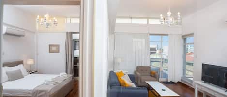 Ein Hotelzimmer mit Bett, einer Couch, einem Fernseher und einem Balkon mit Blick.
