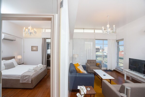Habitación de hotel con cama, sofá, televisión y balcón con vistas.