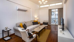 A modern living room with a sofa, armchairs, a coffee table, and a TV. - 1-80 Collection Apt 202 (Limassol)