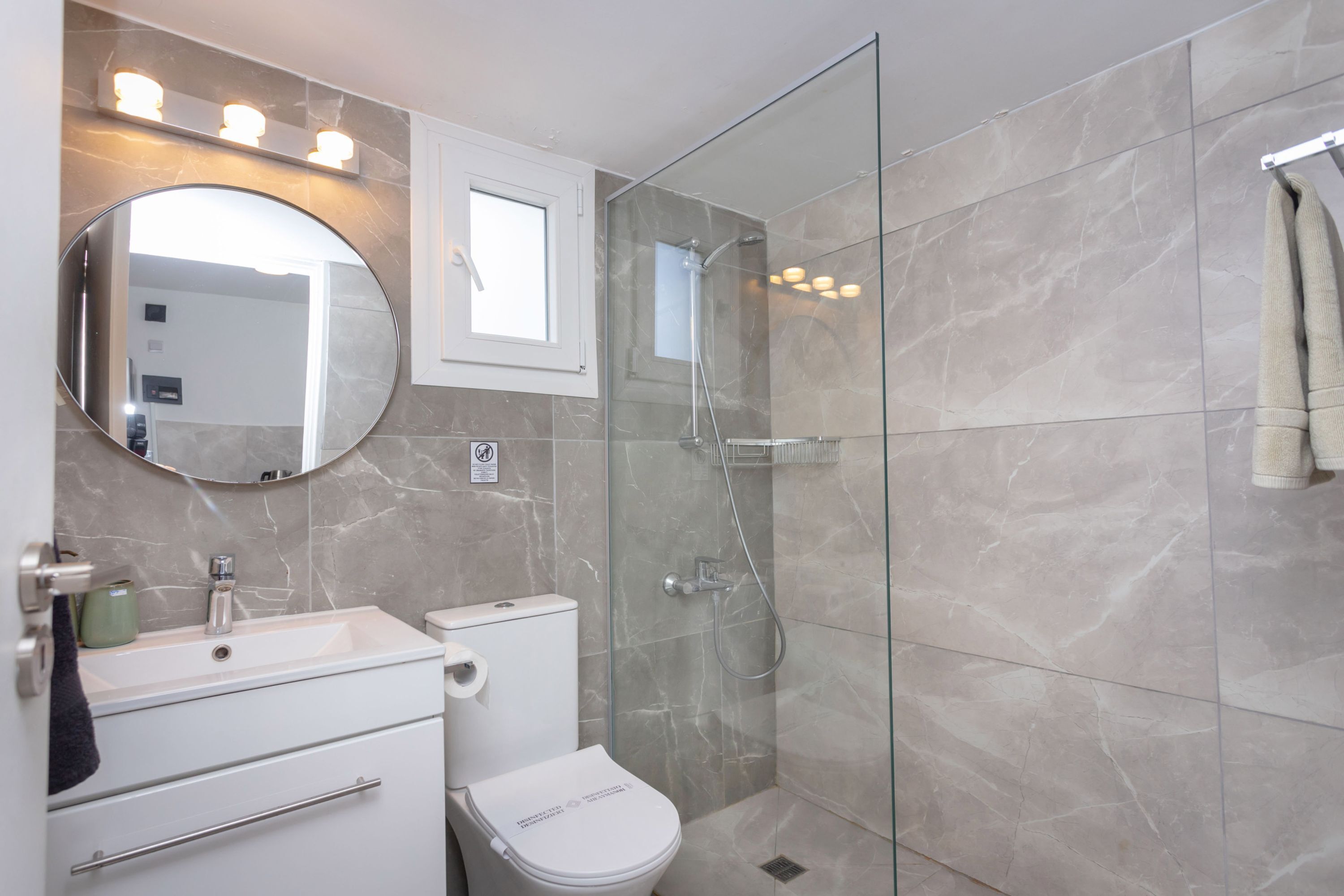 A modern bathroom with a glass-enclosed shower, a white sink, and a toilet.