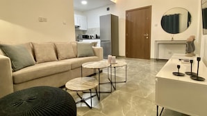 A modern living room with a sofa, two round tables, and a coffee table. - White Arches Sea View Apt No 2 (Limassol)