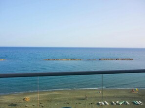 A beach view from a balcony with a clear sky, a sandy beach, and a calm sea. - On the Beach Penthouse (Limassol)