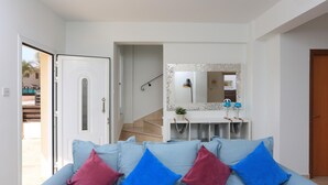 A modern living room with a sofa, a mirror, and a staircase leading to another room. - Seabreeze Villa No 4 (Sotira)