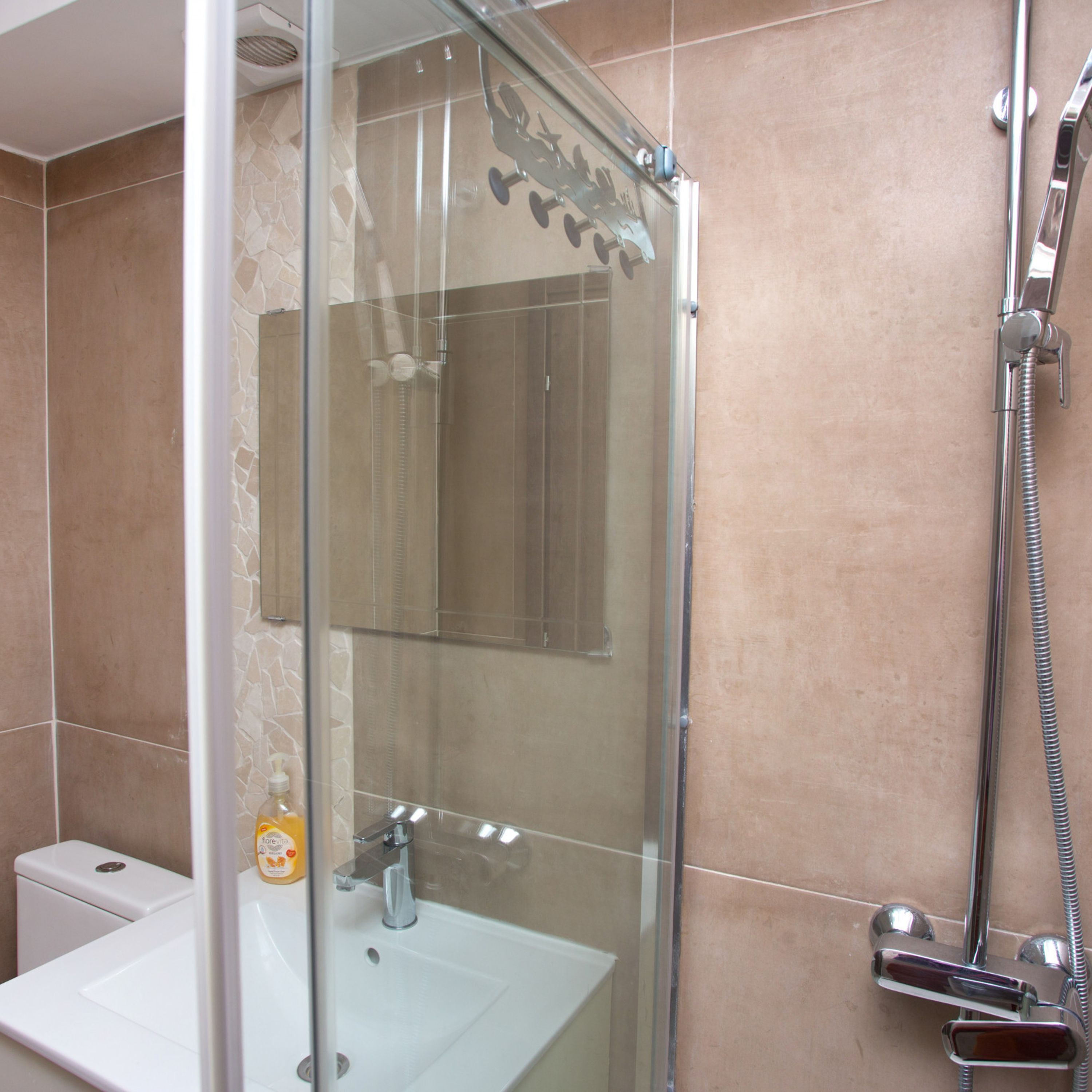 A modern bathroom with a glass-enclosed shower, a white sink, and a toilet.