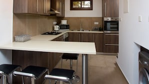 Een moderne keuken met houten kastjes, een centraal eiland met barstoelen, een magnetron, fornuis en oven.