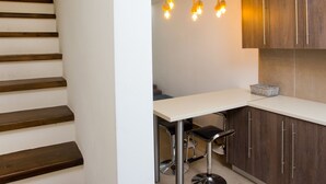 Een moderne keuken met houten kastjes, een wit aanrecht en een barkruk.
