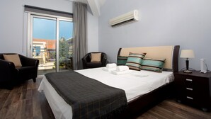 Camera d'albergo con un letto grande, una sedia, un comodino e una finestra con vista su edifici e spazi verdi.