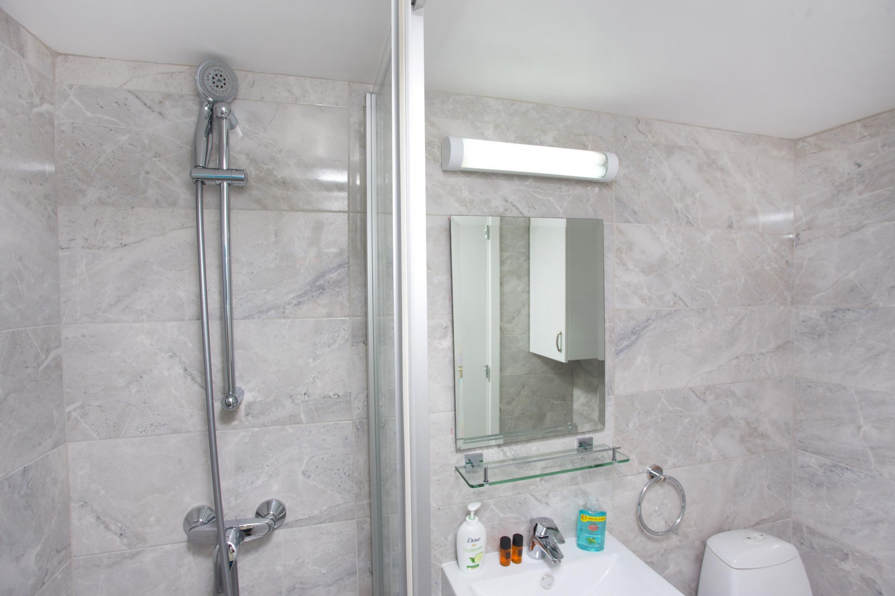Un baño con ducha, lavabo, espejo y artículos de aseo.
