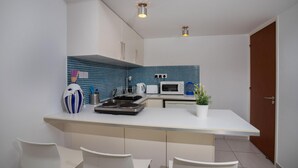 Cozinha moderna com armários brancos, painel de azulejos azuis, ilha central com assentos e micro-ondas.