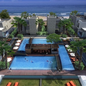 Zona de piscina al terrat amb vista a l'oceà, envoltada de palmeres i edificis moderns.