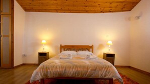A bedroom with a wooden bed, two bedside lamps, and a red carpet. - Old Olive Mill House (Dhoros)