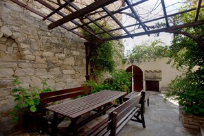 Un edificio de piedra con una banca de madera y una pérgola.