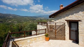 A stone building with a balcony overlooking a mountainous landscape. - Old Olive Mill House (Dhoros)