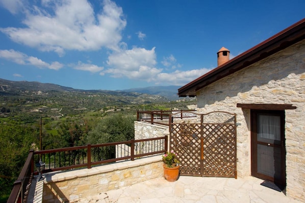A stone building with a balcony overlooking a mountainous landscape.