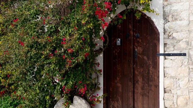 A stone building with a wooden door and a large rock in front. - Old Olive Mill House (Dhoros)