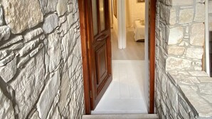 A stone archway leading to a room with a bed and a framed picture on the wall. - Leonys House in Dhoros (Dhoros)
