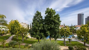 Un jardín ajardinado con senderos, árboles y un edificio al fondo.
