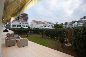 Un patio de hotel con mobiliario exterior, un jardín y vistas de los edificios del hotel.