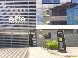 Elite Residence offers a sleek, modern exterior with a glass facade and a welcoming entrance marked by a metal gate.