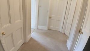 Un pasillo con puertas blancas y alfombra color beige.