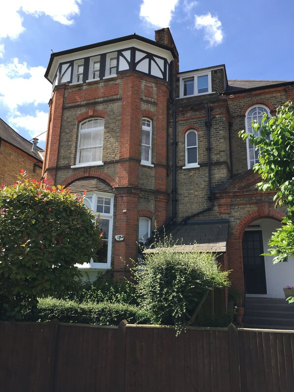 A Victorian-style house with a brick facade, multiple windows, and a prominent corner turret.
