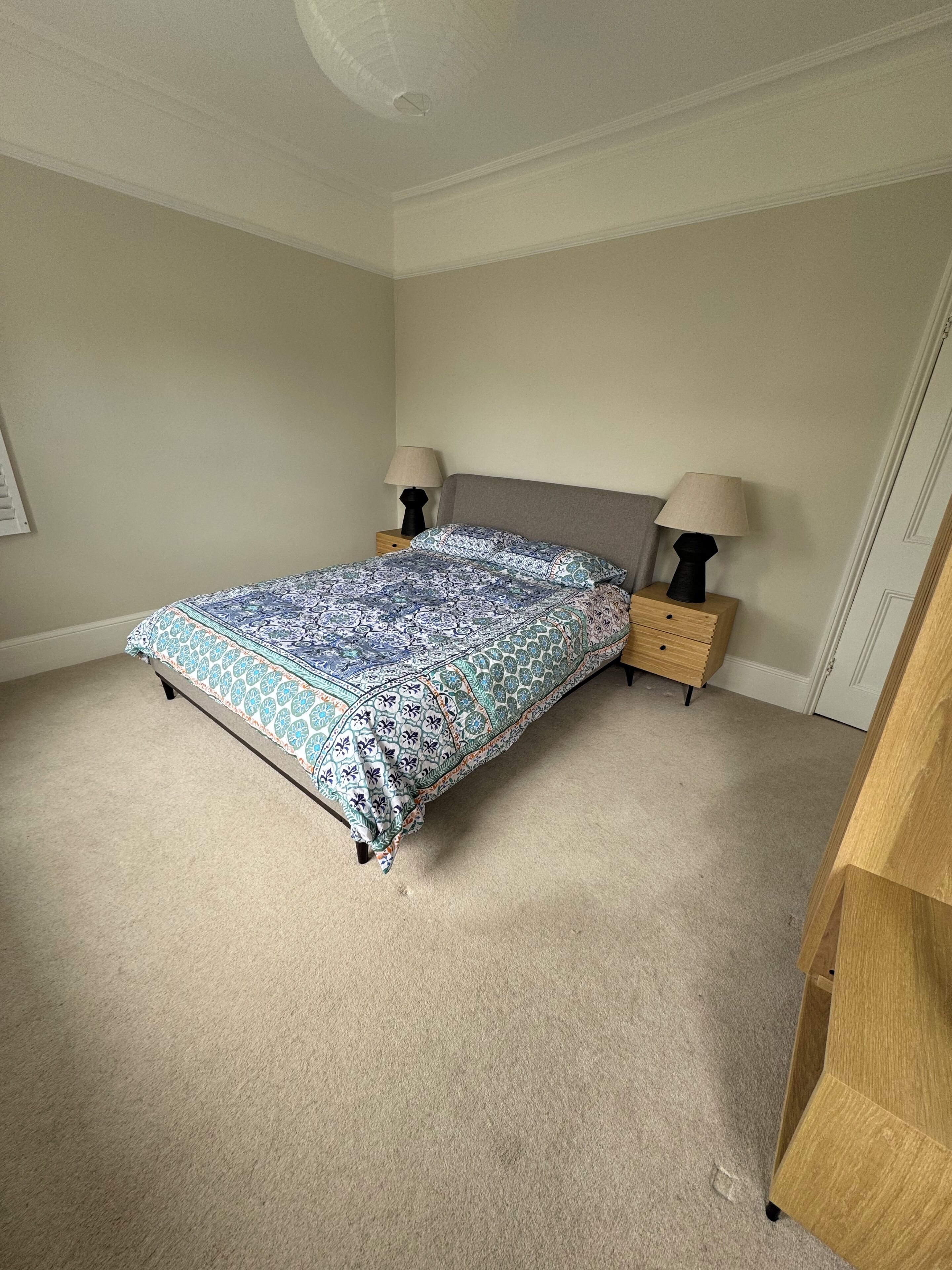 Une chambre à coucher comprenant un lit, deux tables de chevet, une commode et une armoire en bois.