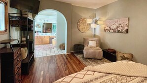 Une chambre à coucher avec un lit, une commode, une chaise, une lampe et un tableau accroché au mur.