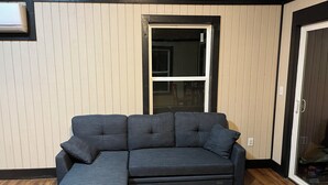A sectional sofa with a matching ottoman in a room with wooden flooring and paneled walls. - New Blue RIdge Mountains Montebello, Virginia with stary stary skies (Montebello)
