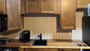 A kitchen with wooden cabinets, a black coffee maker, a sink, and a stove. - New Blue RIdge Mountains Montebello, Virginia with stary stary skies (Montebello)