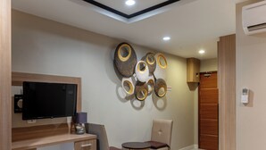 Un dormitorio moderno con una cama, un escritorio con televisor, una silla y decoración en la pared.