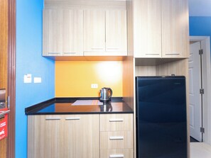 Compact kitchen with a refrigerator, bright accent wall, and no-turbulence zone sign.